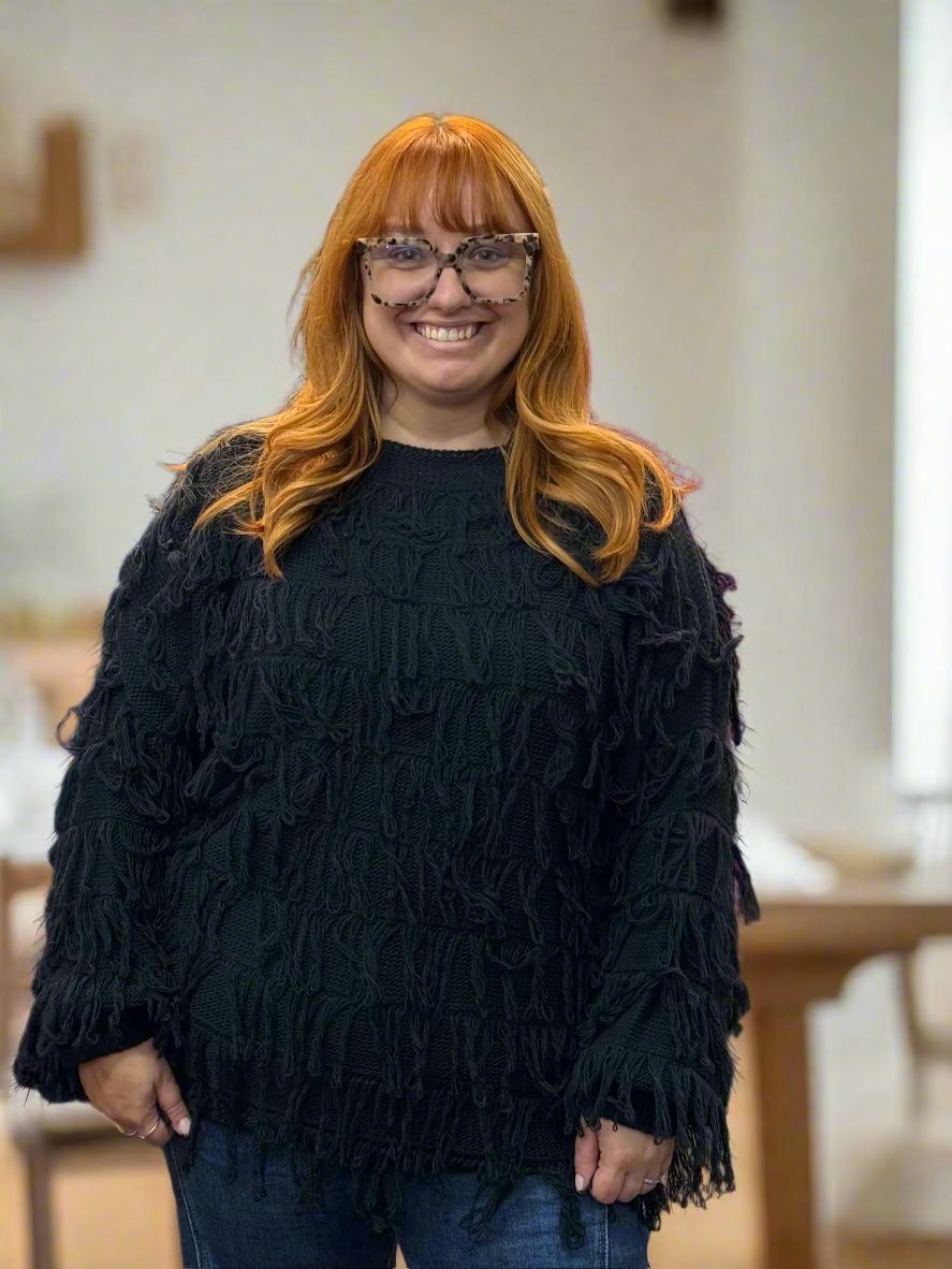 Woman wearing a black fringed sweater in a clothing store